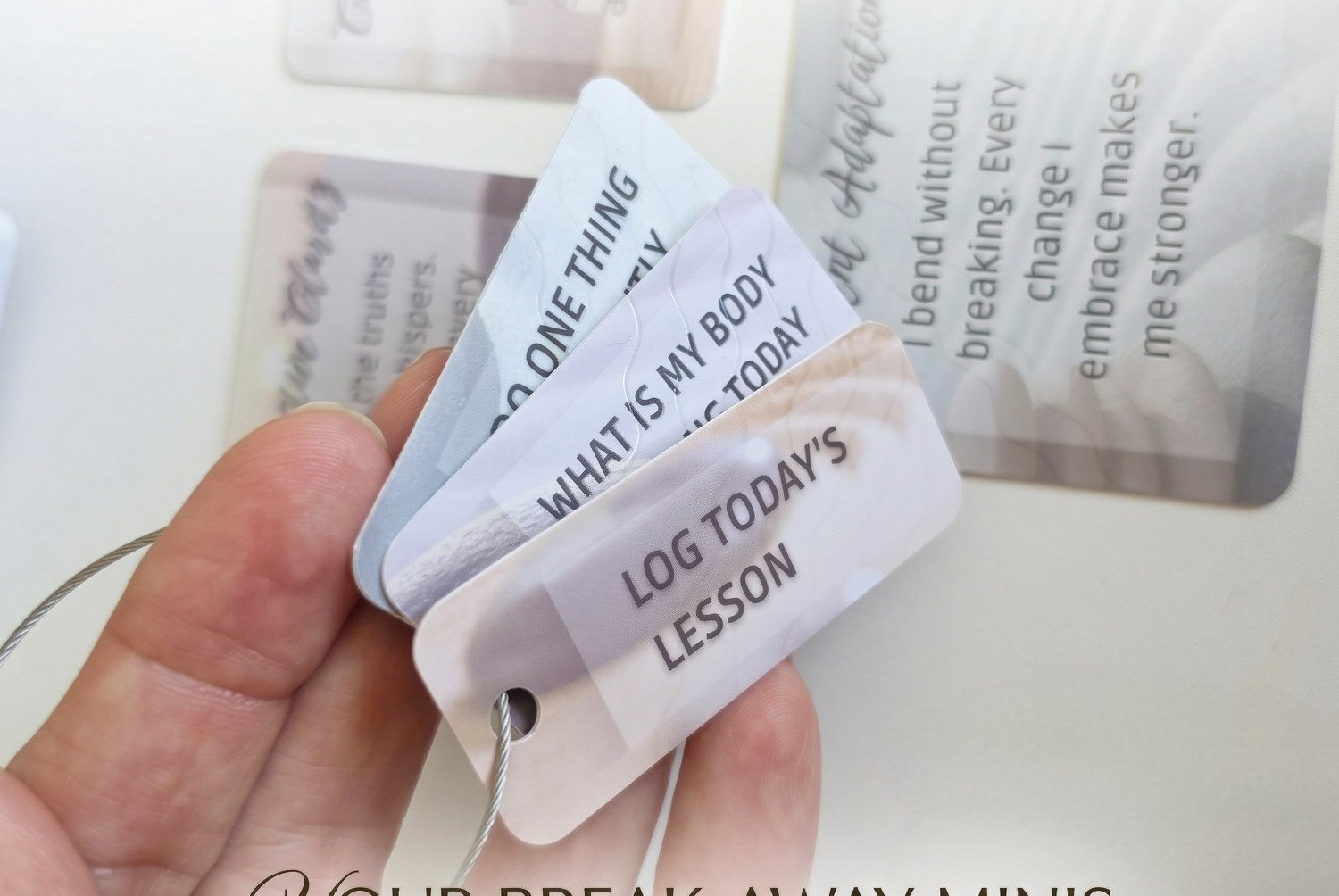 Hand holding a fan of tear-off keychain minis from the affirmation deck